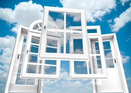 Verschiedene offene weiße Fenster vor blauem Himmel mit Wolken.