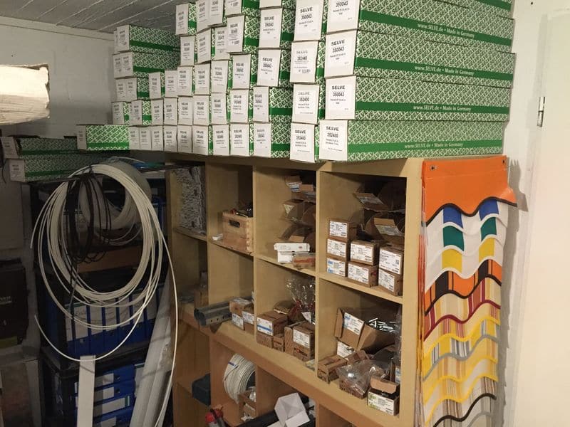 Ein Lagerraum mit Regalen, die zahlreiche beschriftete Kisten und verschiedene Gegenstände enthalten.